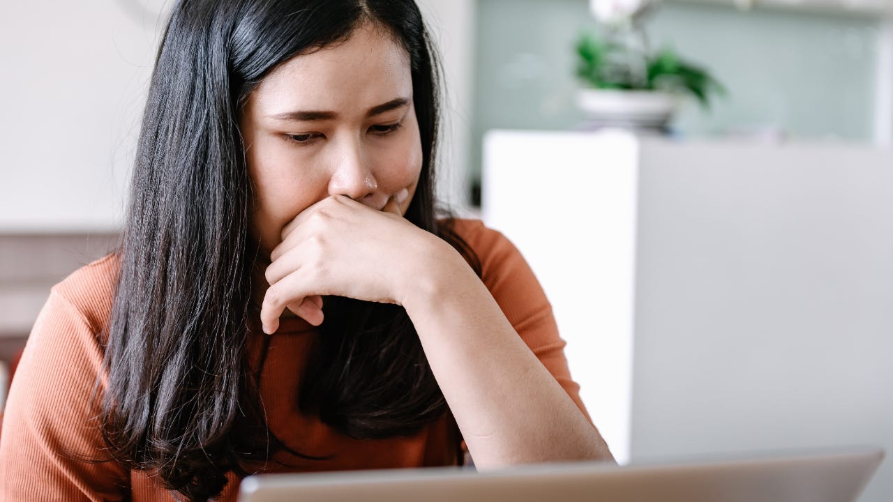Close up of woman leaning on her hand while looking at laptop