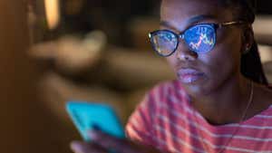 A woman looks at stock charts on her phone.